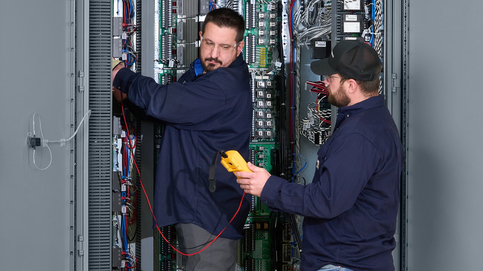 engineers servicing a GE Mark VIe control cabinet during maintenance and configuration work